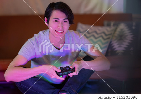 夜のリビングでゲームをする若い男性 115201098