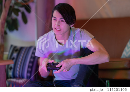 夜のリビングでゲームをする若い男性 115201106