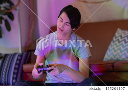 夜のリビングでゲームをする若い男性 夜のリビングでゲームをする若い男性 115201107