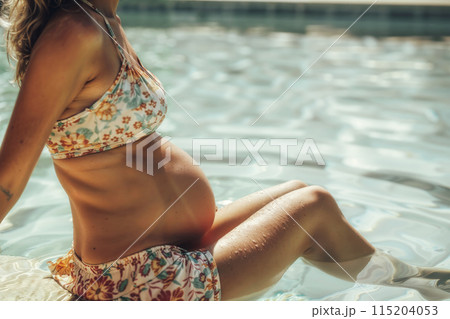 Serene pregnant woman relaxing in pool 115204053