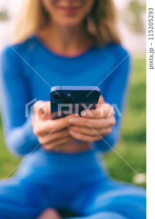 Fitness woman using mobilephone while exercising. Smiling woman doing stretching workout Fitness woman using mobilephone while exercising. Smiling woman doing stretching workout 115205293