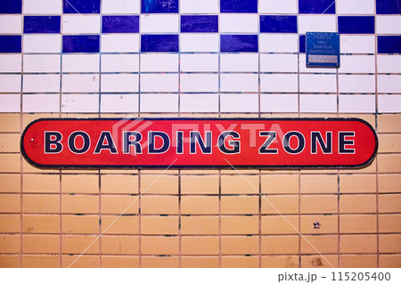 BOARDING ZONE in black and red on tile wall split between tan and white with blue pattern 115205400