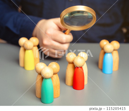 The concept of market segmentation. Target audience, customer care. Market group of buyers. Customer relationship management. Businessman looking through a magnifying glass at figurines of people 115205415