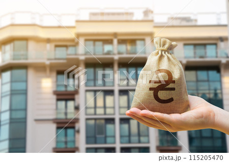 Ukrainian UAH bag against the background of modern high-rise buildings. Investing in the purchase of real estate. Affordable housing and mortgage rates. Renting apartments 115205470