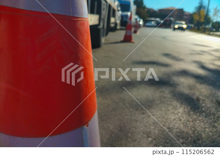 Orange, white traffic cone stands on road separating traffic flows close up, some lanes are completely filled with cars, not free, consequences of accidents, inconvenience, traffic jams, road repairs Orange, white traffic cone stands on road separating traffic flows close up, some lanes are completely filled with cars, not free, consequences of accidents, inconvenience, traffic jams, road repairs 115206562