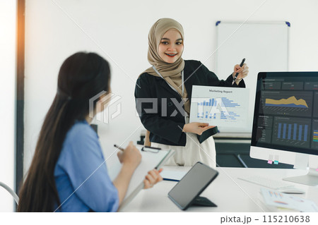 Two colleagues discuss marketing report in modern office meeting. 115210638