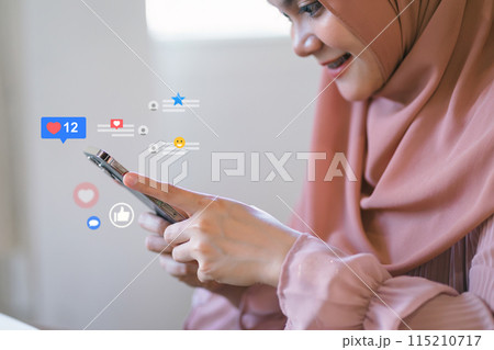 Smiling woman in hijab engaging with social media on smartphone Smiling woman in hijab engaging with social media on smartphone 115210717