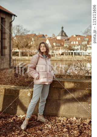 Young beautiful pretty tourist girl in warm hat and coat with backpack walking at cold autumn in Europe city enjoying her travel in Bietigheim-Bissingen, Deutschland. Outdoor portrait of young tourist 115211606