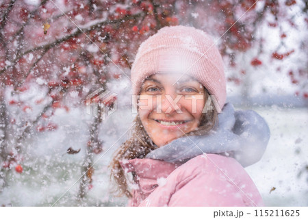 Winter Elegance: Portrait of a Beautiful Girl in a Snowy European Village. Winter lifestyle portrait of cheerful pretty girl. Smiling and having fun in the snow park. Snowflakes falling down Winter Elegance: Portrait of a Beautiful Girl in a Snowy European Village. Winter lifestyle portrait of cheerful pretty girl. Smiling and having fun in the snow park. Snowflakes falling down 115211625