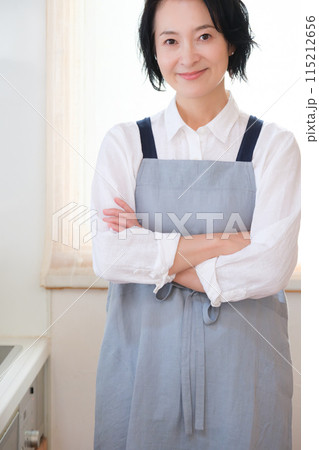 キッチンに立つミドル女性のポートレート 115212656