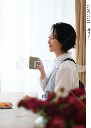 リビングで午後のひとときを過ごすミドル女性 115212695