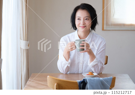 リビングで午後のひとときを過ごすミドル女性 リビングで午後のひとときを過ごすミドル女性 115212717
