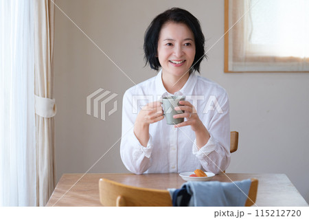 リビングで午後のひとときを過ごすミドル女性 リビングで午後のひとときを過ごすミドル女性 115212720
