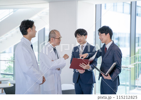 病院で笑顔で会話する男性医師と医薬情報担当者MR 115212825