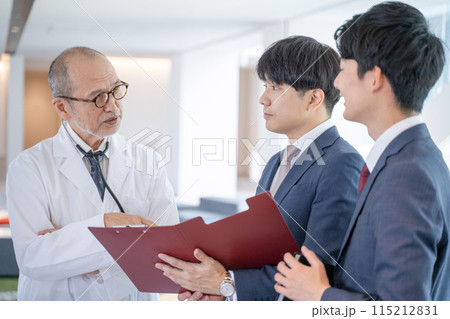 病院で笑顔で会話する男性医師と医薬情報担当者MR 115212831