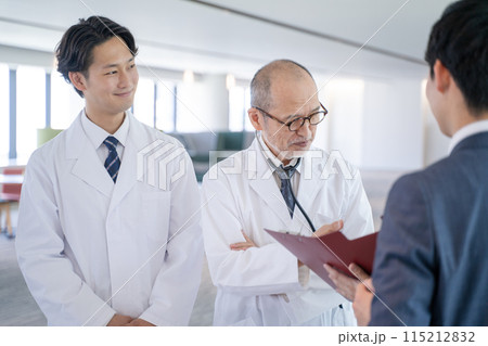 病院で笑顔で会話する男性医師と医薬情報担当者MR 115212832