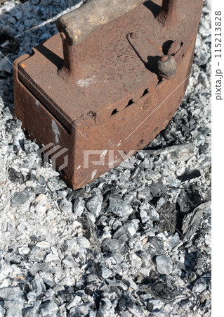 Rare iron working on coals. Against the background of extinct coals. Rare iron working on coals. Against the background of extinct coals. 115213828