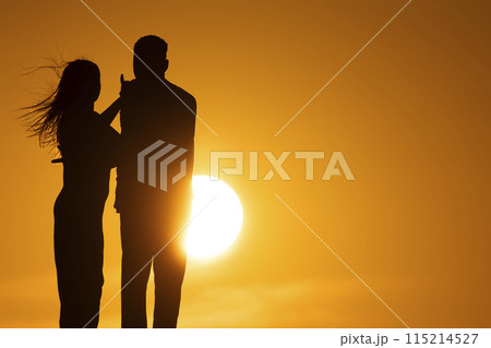 A couple standing in front of a sun with the woman touching the man's arm A couple standing in front of a sun with the woman touching the man's arm 115214527