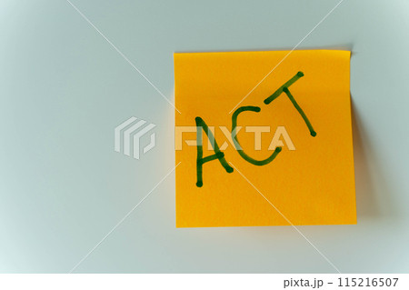 A yellow reminder sticker with the word act written on it. act 115216507