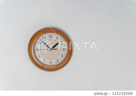 Clock Hanging on Wall in Room. time at 1 hour and 50 minutes. white wall. Round clock Clock Hanging on Wall in Room. time at 1 hour and 50 minutes. white wall. Round clock 115216508