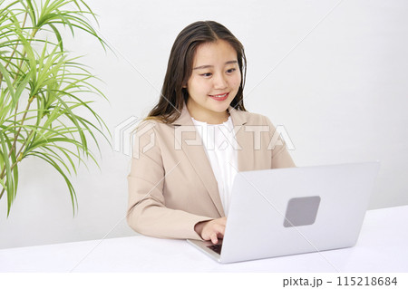 オフィスでパソコンを使ってデスクワークをする若いビジネスウーマン 115218684