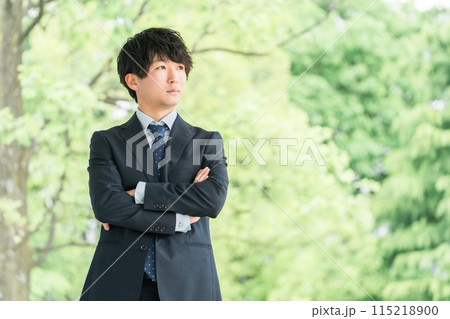 新緑の中にいる若いスーツ姿のビジネスマン・新入社員・転職・就職活動（ビジョン・構想・夢・考える） 115218900