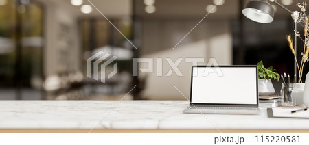 A white marble tabletop features a white-screen laptop computer in a modern office corridor. A white marble tabletop features a white-screen laptop computer in a modern office corridor. 115220581