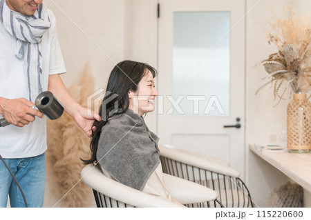 ドライヤーで髪の毛を乾かすスタイリスト・美容師と客の女性 ドライヤーで髪の毛を乾かすスタイリスト・美容師と客の女性 115220600