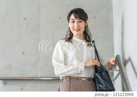 笑顔で階段を降りるビジネスウーマン 笑顔で階段を降りるビジネスウーマン 115223008
