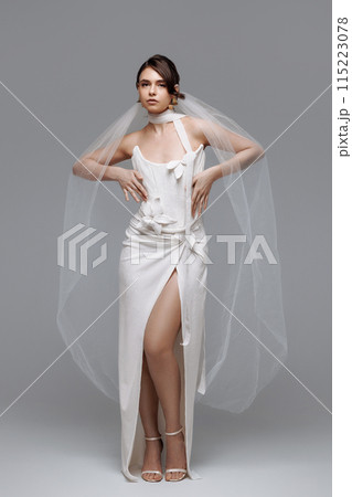 Woman in a white wedding dress on a gray background. 115223078
