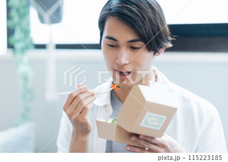 デリバリーで注文した料理を食べる男性 デリバリーで注文した料理を食べる男性 115223185