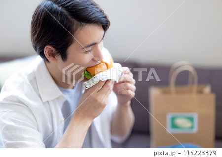 デリバリーで注文した料理を食べる男性 115223379