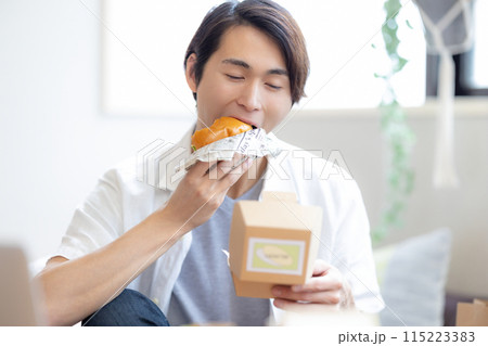 デリバリーで注文した料理を食べる男性 デリバリーで注文した料理を食べる男性 115223383