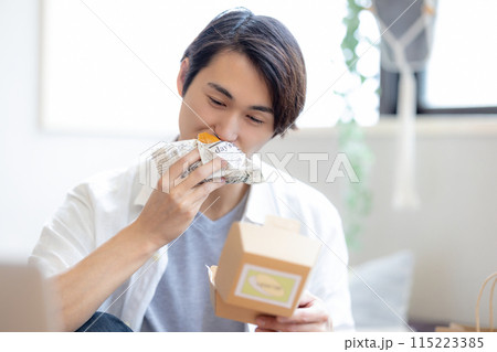 デリバリーで注文した料理を食べる男性 デリバリーで注文した料理を食べる男性 115223385