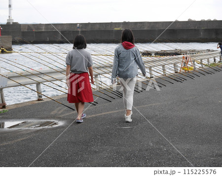 釣り竿が並んだ港を歩く二人姉妹 115225576