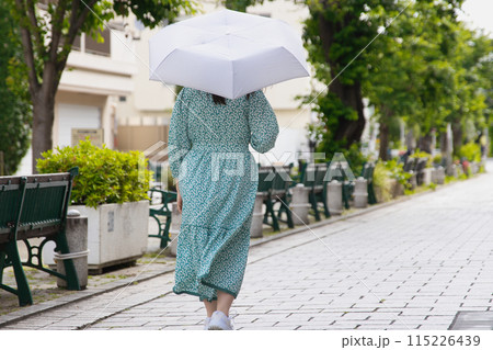 日傘をさして歩く若い女性の後ろ姿 日傘をさして歩く若い女性の後ろ姿 115226439