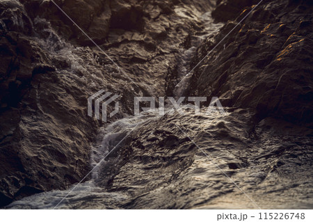 A large rocks surrounded by waves of the ocean A large rocks surrounded by waves of the ocean 115226748