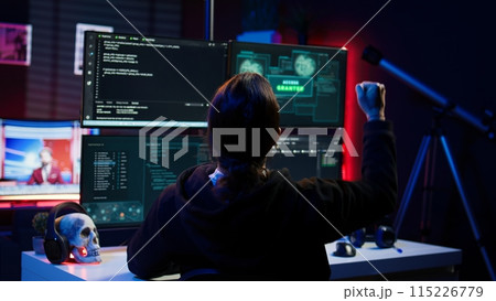 Happy hacker in secret hideout celebrating after managing to hide online activity after stealing data. Cheerful scammer feeling proud after successfully attacking victims using malware, camera B Happy hacker in secret hideout celebrating after managing to hide online activity after stealing data. Cheerful scammer feeling proud after successfully attacking victims using malware, camera B 115226779