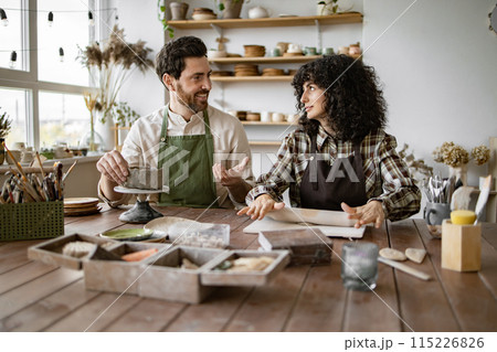 Mature man and woman sculpting clay together in pottery studio 115226826