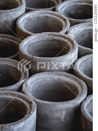 A stack of concrete ring pipes piled and creating a symmetrical arrangement A stack of concrete ring pipes piled and creating a symmetrical arrangement 115226895