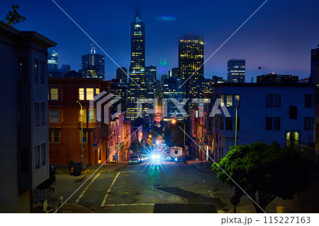 Bright car lights coming up hill from foggy night over downtown San Francisco skyscrapers 115227163