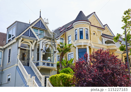 Castle tower on yellow house with large bay windows beside blue house with long staircase and ladder Castle tower on yellow house with large bay windows beside blue house with long staircase and ladder 115227183