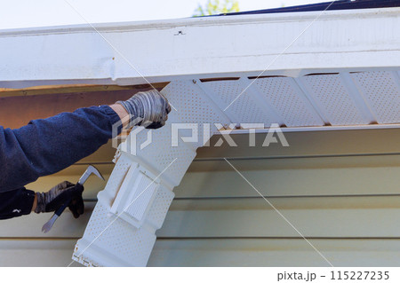 A house master makes repairs to damaged fascia trim during remodeling at home 115227235