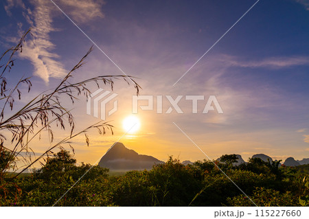 Sunrise or sunset light over mountains with grass in the foreground Low angle view, Amazing colorful sky clouds background 115227660