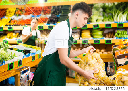 Young salesman puts out packaged potatoes for sale 115228223