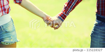 Close up of young couple holding hands, man and woman in love together outdoors 115228327