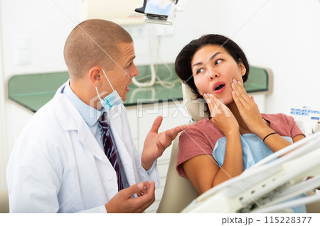 Woman complains of toothache to dentist 115228377