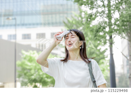 額の汗をハンカチで拭き陽射しを気にする女性 115229498