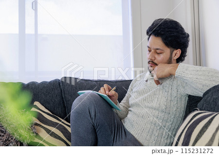 ノートを開いて真剣に悩む男性 ノートを開いて真剣に悩む男性 115231272
