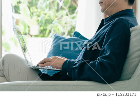 ソファでパソコンを使う男性 115232173
